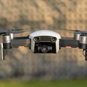 Drone in mid-flight against blurred outdoor background, showcasing technology.